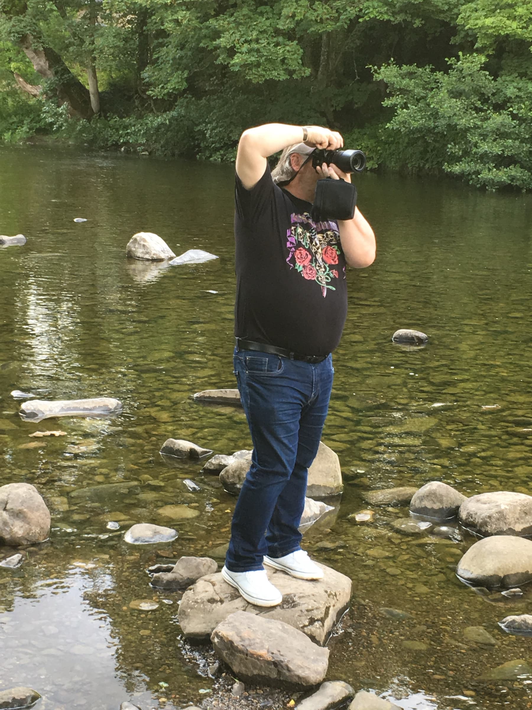Barry Henderson taking a photograph beside a river
